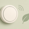 Flat illustration of a round wall thermostat with a wireless signal arc and a leaf representing an energy-saving smart thermostat