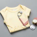 Paper-cut illustration of a hospital bill beside a baby onesie and a stethoscope