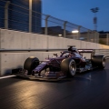 Formula 1-style race car speeding between concrete barriers on a floodlit street circuit at dusk