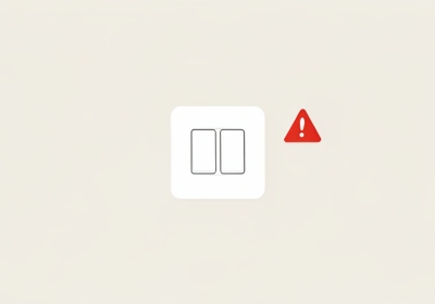 A white electrical outlet with two small blank buttons and a red warning triangle beside it
