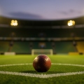 A football on the centre spot of a floodlit stadium pitch at dusk