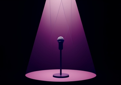A single microphone on a spotlit stage with faint marionette strings descending toward it