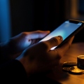 A person messaging on a phone at night with a coin-credit balance concept, suggesting a paid-chat dating trap