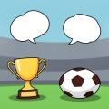 A small man-of-the-match trophy beside a football on grass under stadium lights