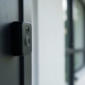 A modern video doorbell mounted beside a front door in daylight