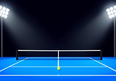 An empty blue tennis court at night under bright stadium floodlights with a single ball near the baseline