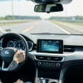 A driver's hands near the wheel of an electric car with a driver-assistance display on the dashboard